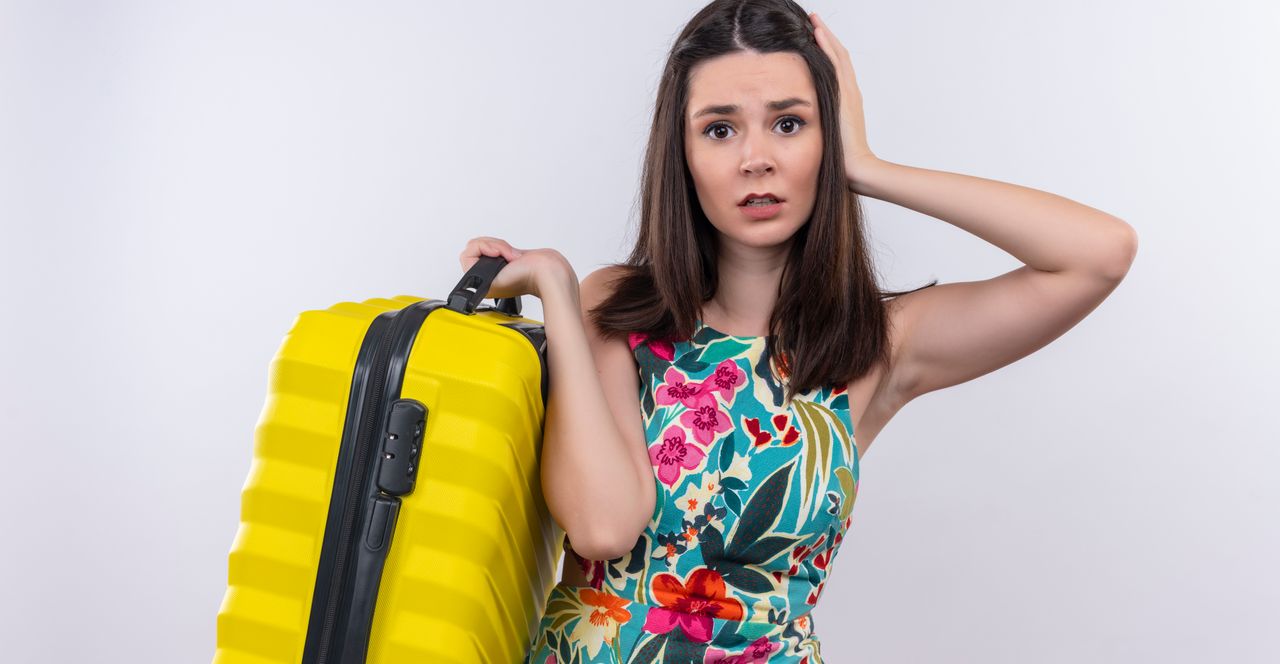 Mujer preocupada por la falta de planificación en el viaje, sosteniendo una maleta amarilla y con expresión de estrés.
