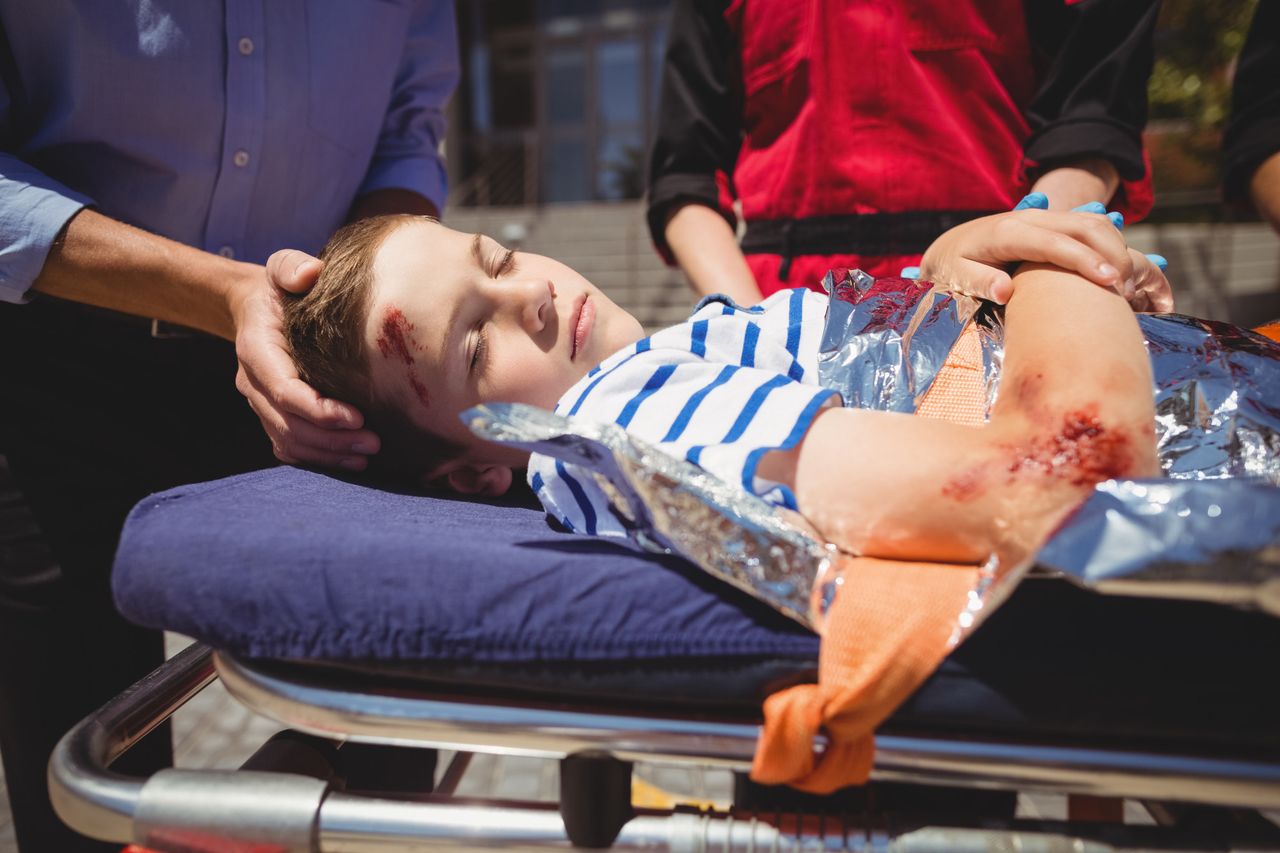 Niño herido siendo atendido por paramédicos tras un accidente. Importancia del seguro de accidentes para emergencias infantiles.