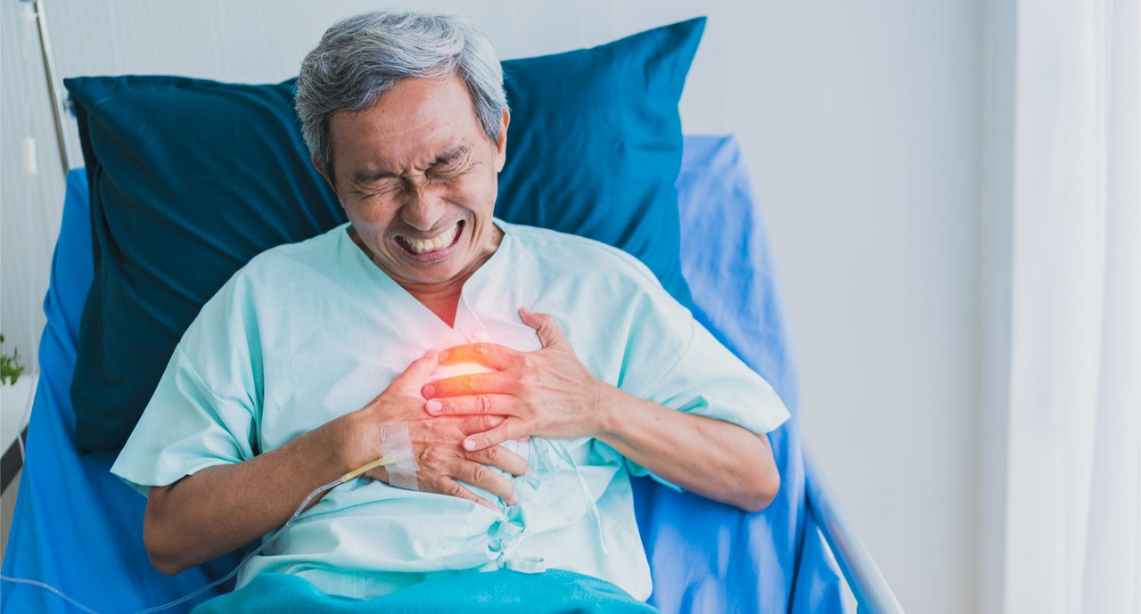 Hombre mayor con expresión de dolor agudo en el pecho, acostado en una cama de hospital, representando enfermedades cardiovasculares
