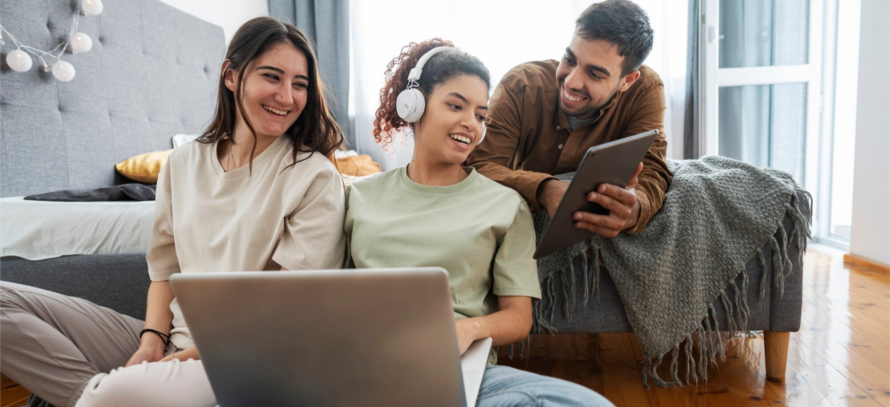 Grupo de jóvenes millennials compartiendo tecnología y aprendizaje digital en un ambiente relajado y moderno.