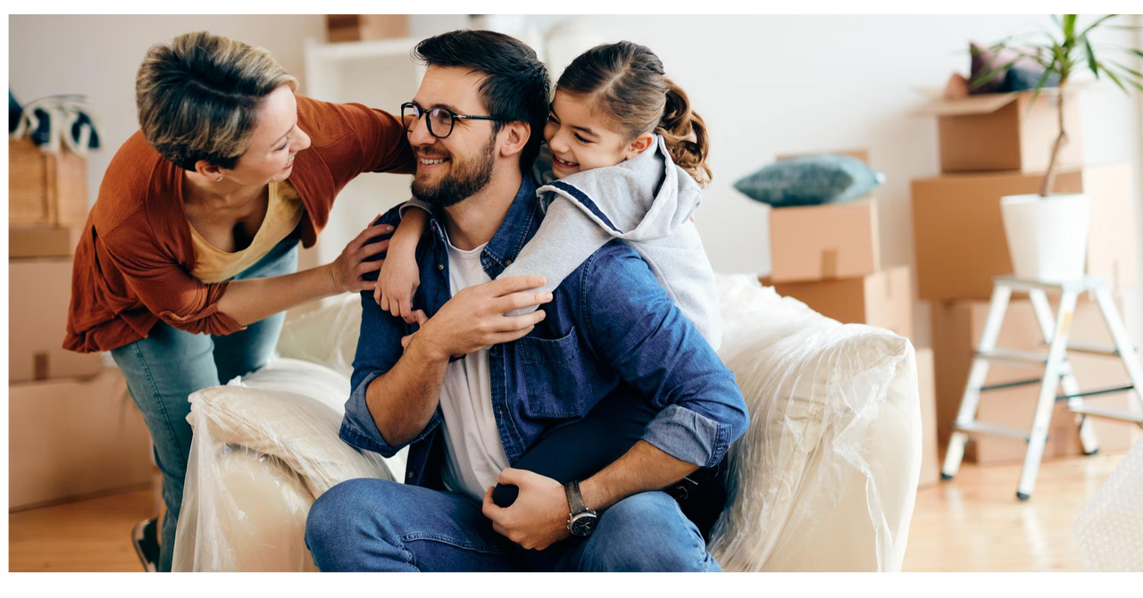 Familia feliz en su nuevo hogar, rodeada de cajas de mudanza, disfrutando un momento juntos mientras se acomodan.