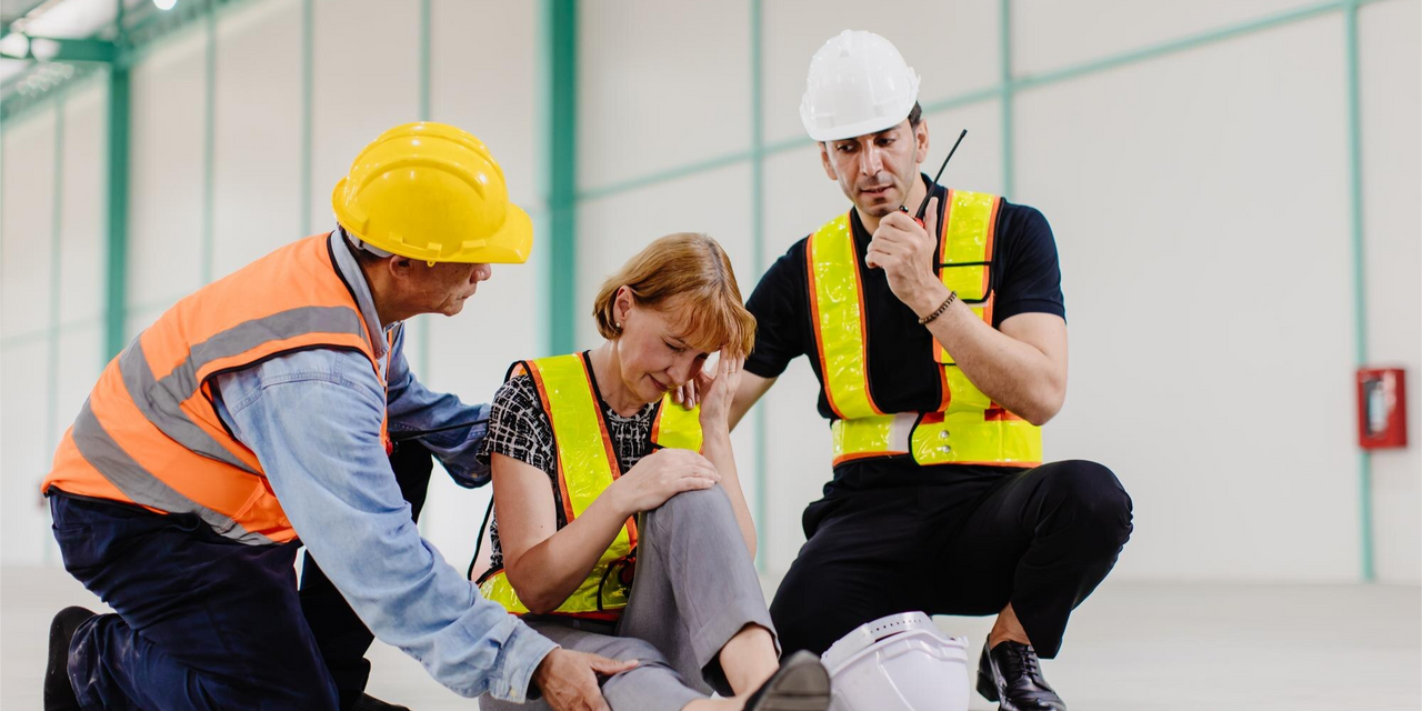 Trabajadores auxiliando a una compañera tras un accidente laboral en una obra en construcción.