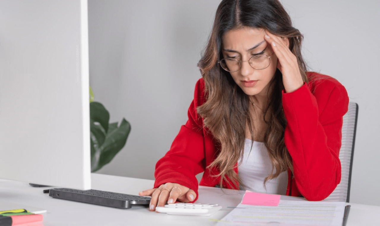 Mujer joven preocupada revisando cuentas en su escritorio tras gastar más de lo normal, destacando la importancia del ahorro para independizarte