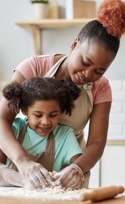 Madre e hija disfrutando de un momento especial en la cocina, simbolizando la importancia de proteger a la familia con un seguro de vida.